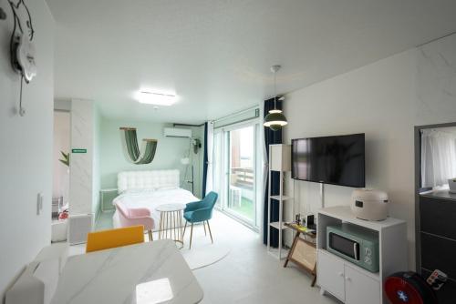 a living room with a room with a table and a television at Jeju Aneuk Stay in Murŭng-ni