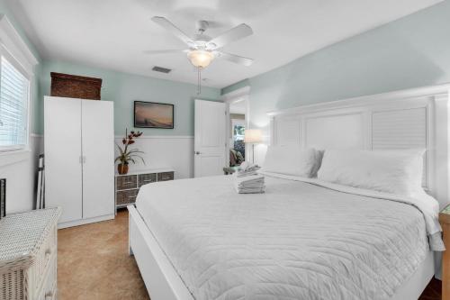 a bedroom with a white bed and a ceiling fan at Peacock Way bungalow in Holmes Beach