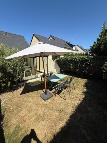 - une table et des chaises sous un parasol dans la cour dans l'établissement Maisonnette refaite à neuf - Jardin - Piscine, à Guidel