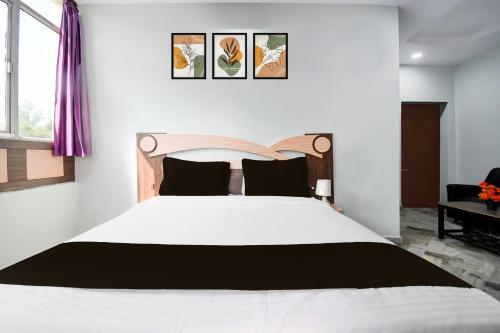 a bedroom with a large white bed with black pillows at Super Townhouse Jyoti Mahal Road Rayagada in Rāyagada
