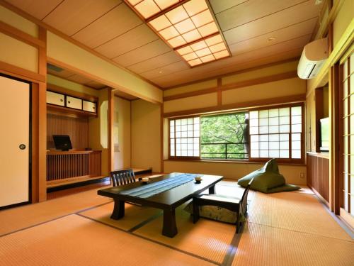 a room with a table and a bench and windows at 藤龍館-TOURYUKAN-Yunokamionsen in Yunokami