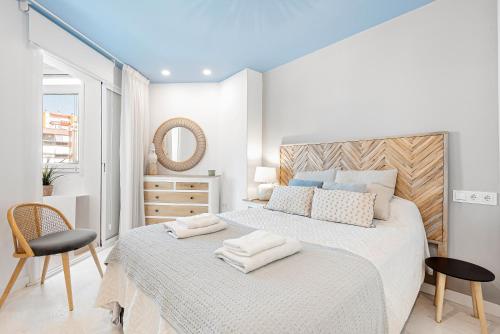 Un dormitorio blanco con una cama grande y una silla. en Plazamar 044, en Torre del Mar