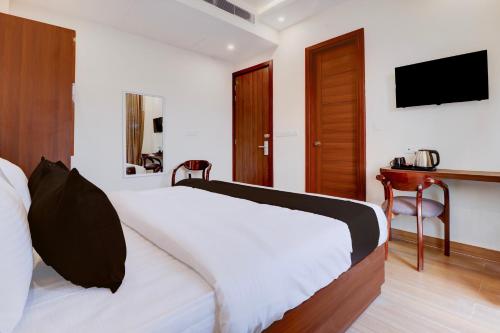 a bedroom with a white bed and a television at Super Townhouse Oak FRI Dehradun Formerly Hotel EL Portrait in Dehradun