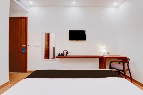 a bedroom with a bed and a desk with a television at Super Townhouse Oak FRI Dehradun Formerly Hotel EL Portrait in Dehradun