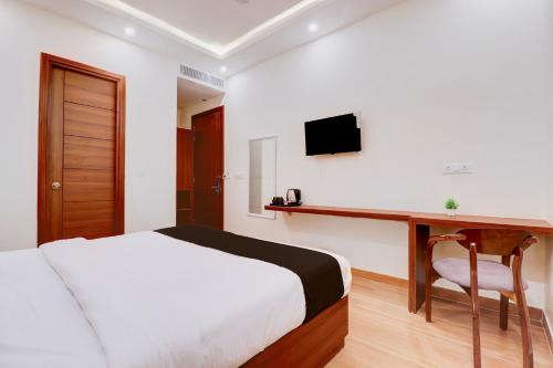 a bedroom with a bed and a desk with a television at Super Townhouse Oak FRI Dehradun Formerly Hotel EL Portrait in Dehradun