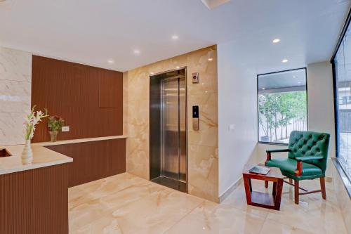 a bathroom with a green chair and a glass door at Super Townhouse Oak FRI Dehradun Formerly Hotel EL Portrait in Dehradun