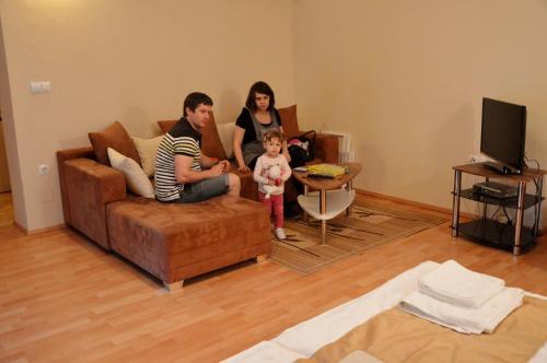 a family sitting on a couch in a living room at Turistična Kmetija Čebelji Gradič in Rogašovci