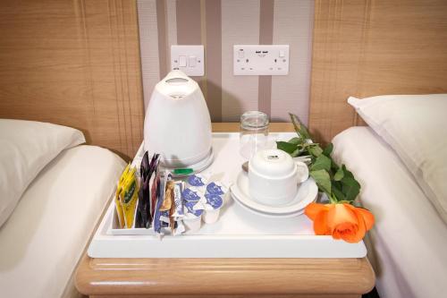 a tray with a table with a coffee maker on a bed at Fairway Hotel in London