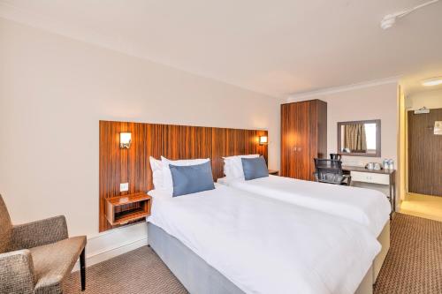 a hotel room with a large bed and a desk at Palms Hotel & Retreat By Palette London Romford in Hornchurch