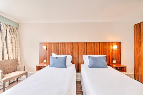 a hotel room with two beds and a chair at Palms Hotel & Retreat By Palette London Romford in Hornchurch