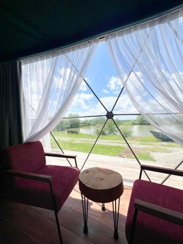 a room with a large window with chairs and a table at Chadir yurd glamp in İsmayıllı