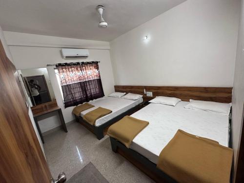 a bedroom with two beds and a window in it at Hotel Shree Ganesh in Somnath