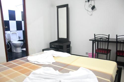 a bedroom with a bed and a bathroom with a mirror at Swiss Grand Lanka in Homagama