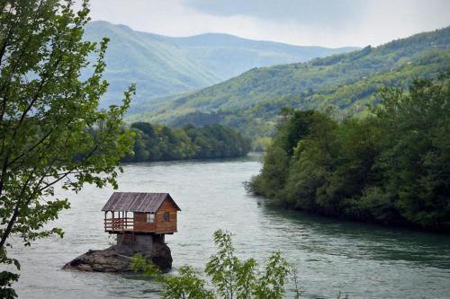 a house on a rock in the middle of a river at Viola i Detelina Apartments in Perućac