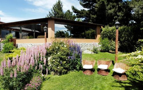 a garden with chairs and flowers in front of a building at Hotel Sierra Nevada in El Calafate