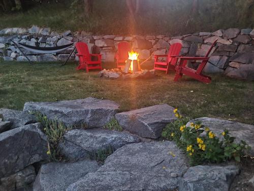 two red chairs sitting around a fire in a yard at Fresh Studio Apartment in Central Rossland in Rossland