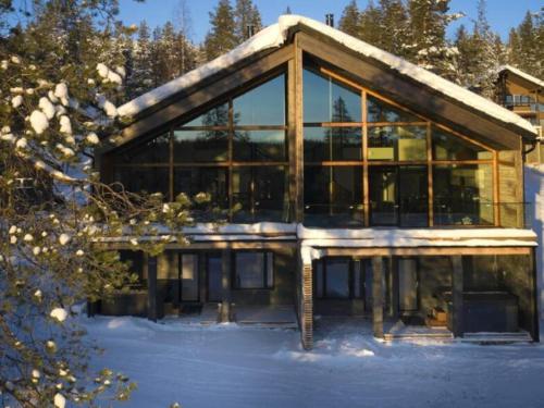 a large building with glass windows in the snow at Villa Lux B by Aavalevi Holidays in Levi