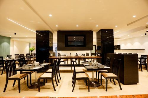 a restaurant with black tables and chairs and a television at Spree Manor Hotel in Aurangabad