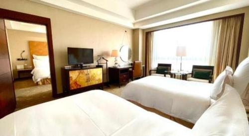 a hotel room with two beds and a mirror at Kunshan Newport Hotel in Suzhou