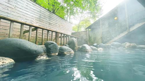 a pond with rocks in the water next to a building at Hotel Floracion Nasu in Nasu