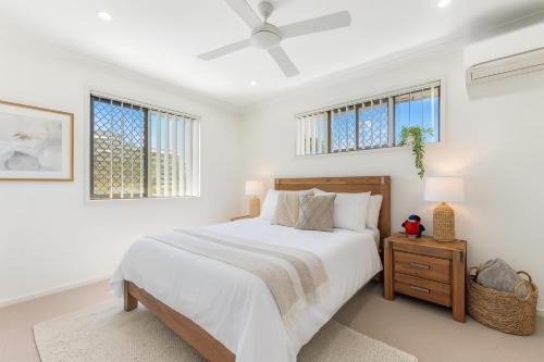 a white bedroom with a bed and two windows at Carseldine Grove in Brisbane