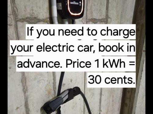 a sign that says if you need to charge your electric car book in advance at HaPPy Inn GOLD Studio, self check-in, Parking in the underground garage in Vilnius