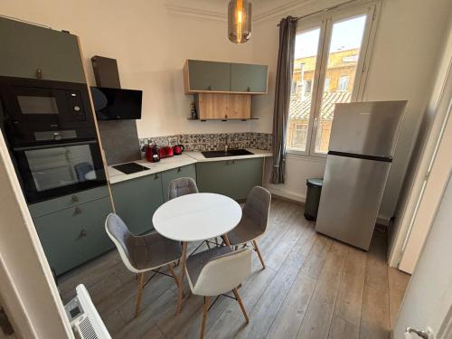 une cuisine avec une table, des chaises et un réfrigérateur dans l'établissement L'Atelier D'AIX, à Aix-en-Provence