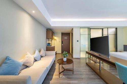 a living room with a couch and a flat screen tv at AURAYA BY SUNING NANJING XUZHUANG in Nanjing