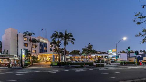 an empty city street at night with palm trees and buildings at Hotel Diana Woolloongabba in Brisbane