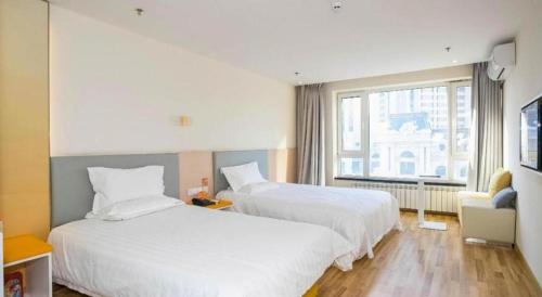 a hotel room with two beds and a window at 7 Days Inn Harbin West Railway Station in Harbin