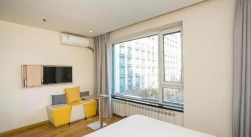 a bedroom with a bed and a tv and a window at 7 Days Inn Harbin West Railway Station in Harbin
