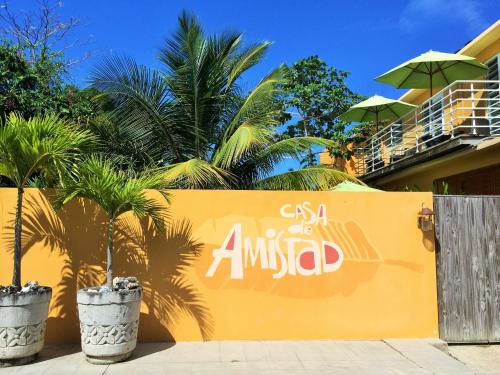 a sign on a yellow wall with palm trees at Casa de Amistad Guesthouse in Vieques