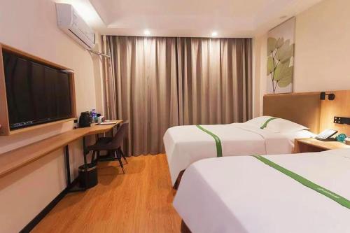 a hotel room with two beds and a flat screen tv at GreenTree Inn Puyang Pushang Huanghe Road in Puyang
