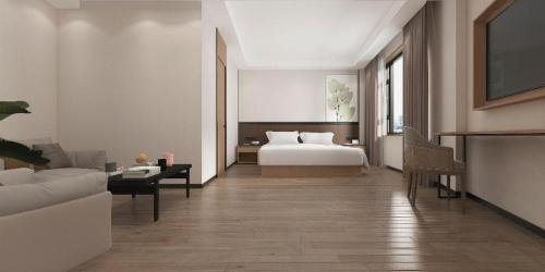 a bedroom with a bed and a living room at GreenTree Inn Puyang Pushang Huanghe Road in Puyang