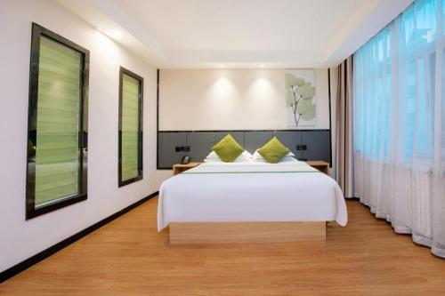 a bedroom with a white bed and a large window at GreenTree Inn Puyang Pushang Huanghe Road in Puyang