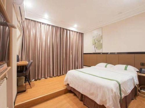 a hotel room with a large bed and a desk at GreenTree Inn Puyang Pushang Huanghe Road in Puyang