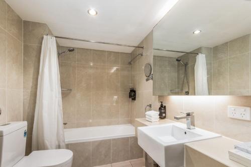 a bathroom with a sink and a toilet and a tub at Hotel Diana Woolloongabba in Brisbane