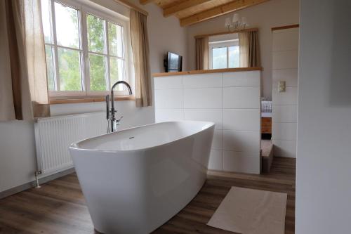 un bagno con una grande vasca bianca in una stanza di Apartmenthaus Eisenstraße a Lunz am See