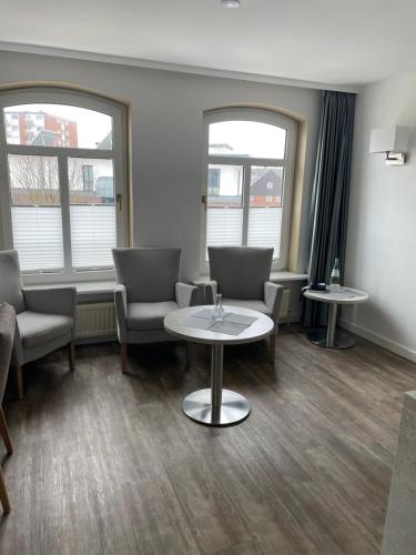 a waiting room with chairs and a table and two windows at Hotel Sylter Hof in Westerland (Sylt)
