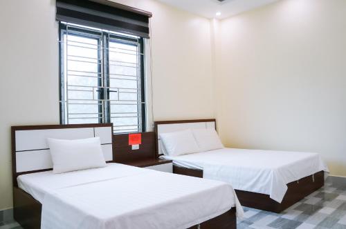 deux lits dans une chambre avec une fenêtre dans l'établissement Cat Ba Sky Home, à Xuan Dam