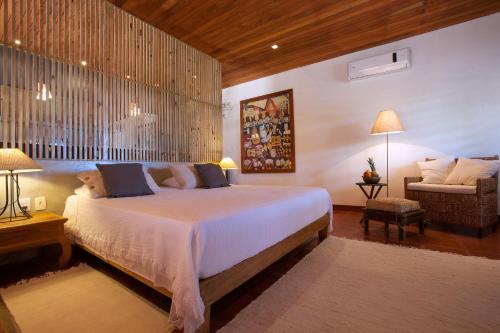 a bedroom with a large bed and a chair at Hotel Villaggio Tudo Bom in Uruau