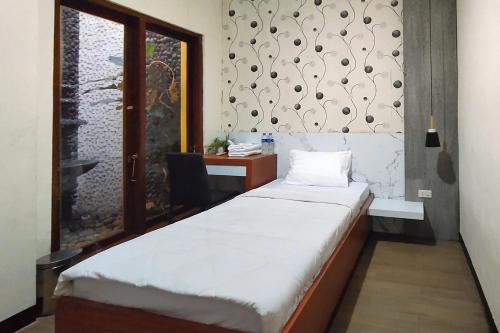 una stanza con un letto, una scrivania e una finestra di INNCA - Villa Jatidiri, Semarang a Jatingaleh