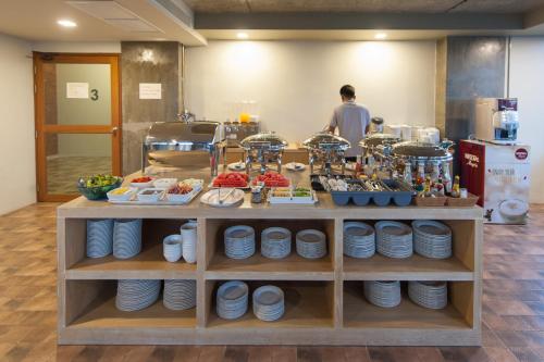 a food counter with plates and a man in a kitchen at The Sixteenth Naiyang Beach Hotel- Free Schedule Airport Shuttle in Nai Yang Beach