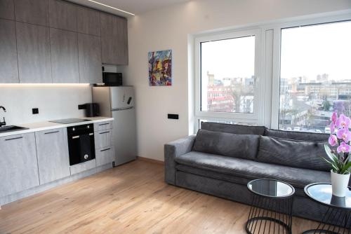 un salon avec un canapé et une cuisine dans l'établissement Sunlit City Loft- Prime Views, à Vilnius