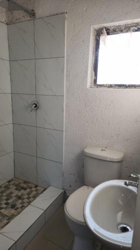 a bathroom with a toilet and a sink and a window at GenAyah Hotel & Safari in Mtimba