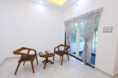 two chairs and a table in a room with a window at Star Eden Residency in Virāmpattinam