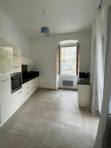 une grande cuisine blanche avec une fenêtre et un sol carrelé dans l'établissement côté théâtre, à Bastia