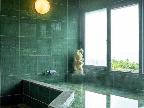 a green tiled bathroom with a tub and a window at Haruhoo Resort ISHIGAKI in Ishigaki Island
