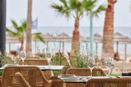 a table with chairs and wine glasses on the beach at Atlantica Callisto in Ayia Napa