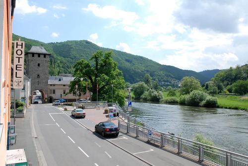 a street with cars driving down a road next to a river at Hotel Restaurant LAHNHOF in Dausenau